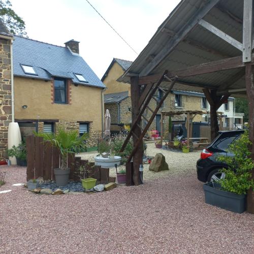 un pavillon avec une table et des plantes devant une maison dans l'établissement Gites Repère des Fées, à Pleugueneuc