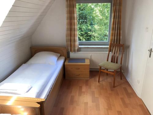 a small bedroom with a bed and a chair at Mühlenweg- Tante Lise in Süderlügum