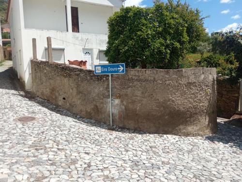 a blue street sign sitting next to a stone wall at EiraDouro - Casa Oliveira in Mós