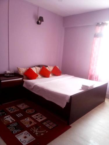 1 dormitorio con 1 cama grande con almohadas rojas en Field Residency Inn, en Shillong
