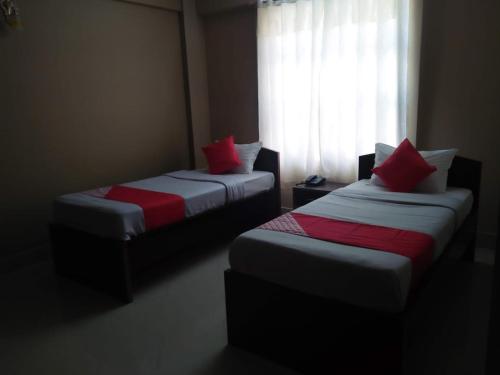 Field Residency Inn في شيلونغ: سريرين مع وسائد حمراء في غرفة مع نافذة