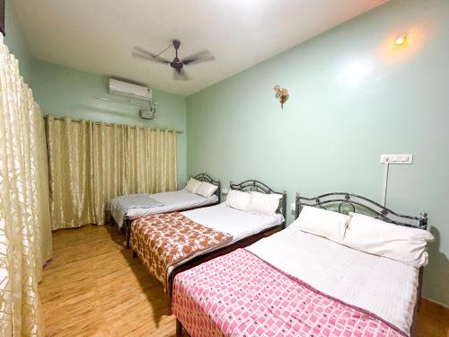 a room with three beds and a ceiling at JFZ Homestay in Honāvar