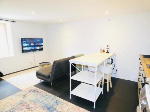 ein Wohnzimmer mit einem Stuhl, einem Tisch und einem TV in der Unterkunft Studio St Julien near Geneva in Saint-Julien-en-Genevois