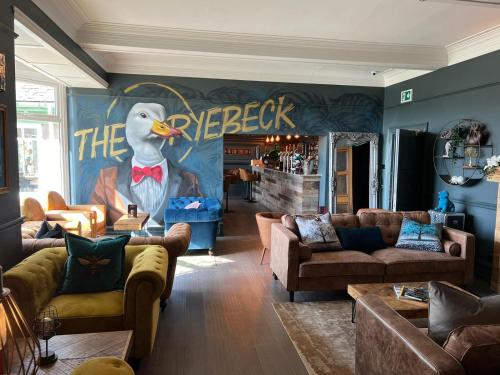 a living room with couches and a chicken painting on the wall at The Ryebeck Hotel in Bowness-on-Windermere