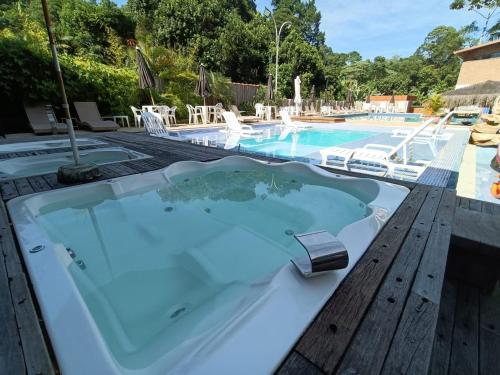 a jacuzzi tub on a deck next to a swimming pool at EcoHotel Vale do Sol in Embu