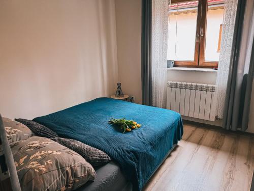 a bed with a blue blanket and flowers on it at Fotuso House in Majdany Wielkie