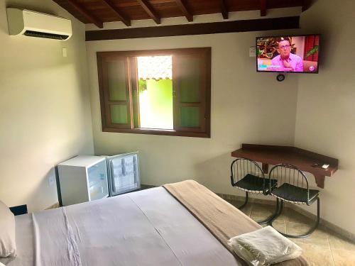 um quarto com uma cama e uma televisão na parede em Pousada e Camping Recanto da Praia em Capitólio