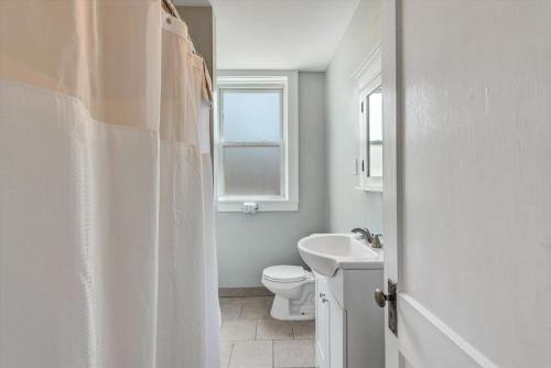 a white bathroom with a toilet and a sink at 2e Tower Grove Getaway in Richmond Heights