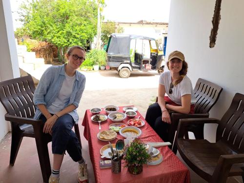 Ein Mann und eine Frau sitzen an einem Tisch mit Essen in der Unterkunft Khajuraho Rancho in Khajurāho