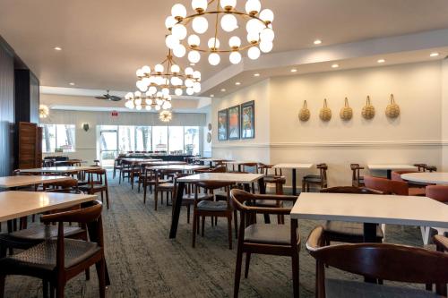 a dining room with tables and chairs and a chandelier at Embassy Suites by Hilton Deerfield Beach Resort & Spa in Deerfield Beach