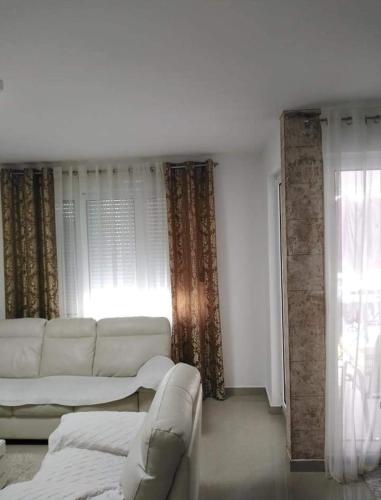 a living room with a white couch and a window at D&D Apartman in Bar