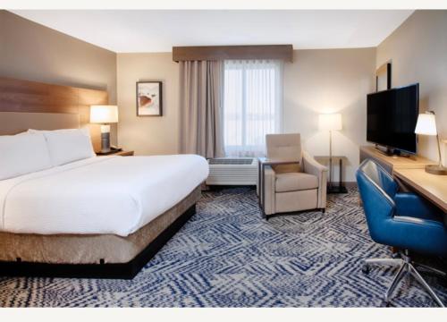 ein Hotelzimmer mit einem Bett und einem Flachbild-TV in der Unterkunft Candlewood Suites Detroit Sterling Heights, an IHG Hotel in Waldenburg