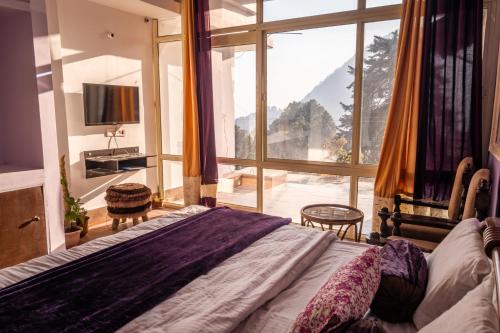 een slaapkamer met een bed en een groot raam bij Dew Drops Homestay in Nainital