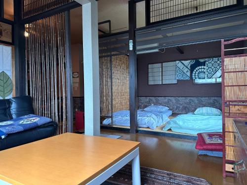 Zimmer mit 2 Etagenbetten und einem Tisch in der Unterkunft ゲストハウス れんげ苑 in Shimosato