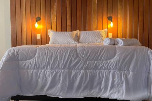 1 cama blanca grande con sábanas y almohadas blancas en Chalé Causo Bão en Costas