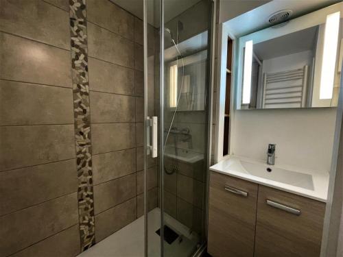 ein Bad mit einer Dusche, einem Waschbecken und einem Spiegel in der Unterkunft Résidence Jetay - 3 Pièces pour 7 Personnes 464 in Les Menuires