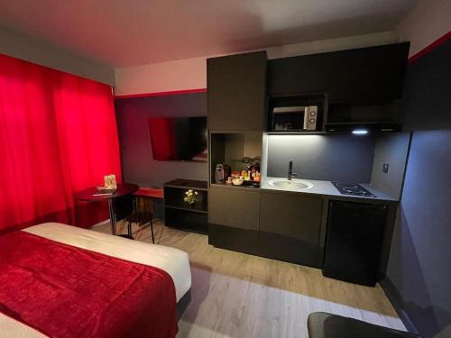 a room with a bed and a kitchen with red curtains at Disney 'Xperience - Parc 10 min - 3pers in Esbly