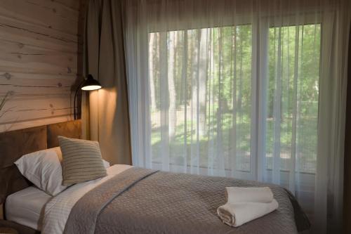 a bedroom with a bed and a large window at Miško namelis - mieste in Utena