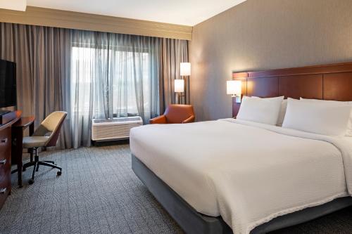 a hotel room with a large bed and a desk at Courtyard Long Beach Airport in Long Beach