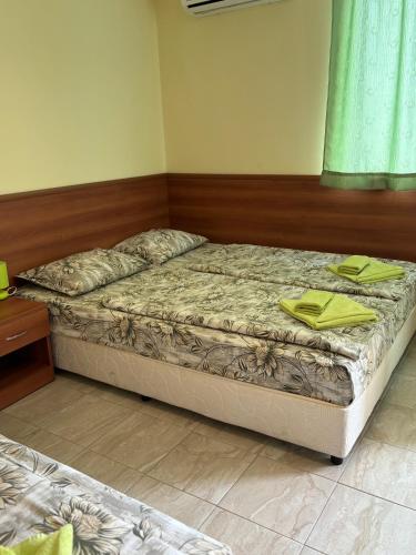a bedroom with a bed with yellow towels on it at Семеен хотел САМИ in Kranevo