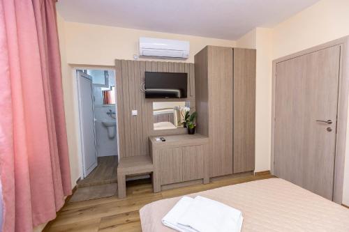 a room with a bed and a tv and a bathroom at Family Hotel Ambrozia in Sandanski