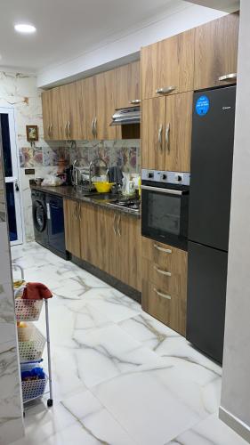 a kitchen with wooden cabinets and black appliances at Achakar in Tangier