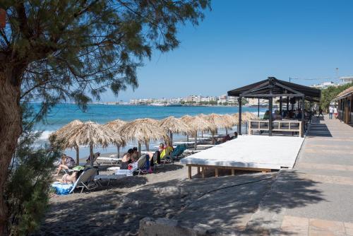 a beach with people sitting under umbrellas and the water at Estia Luxury Apartment in Ierápetra