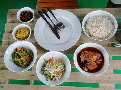 una mesa con platos de comida y tazones de comida en Surf And Stay Arugam Bay en Arugam Bay