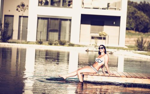 a woman in a bikini sitting on a dock in the water at Greenhouse-Sonnengolf in Zsira