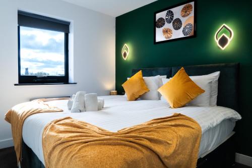 sypialnia z dużym białym łóżkiem z żółtymi poduszkami w obiekcie Midsummer Apartments "Free On-Site Parking & Sky TV" w mieście Peterborough
