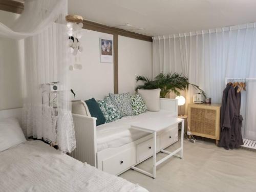 a bedroom with a white couch and a bed at Cottenbeach2 in Sokcho