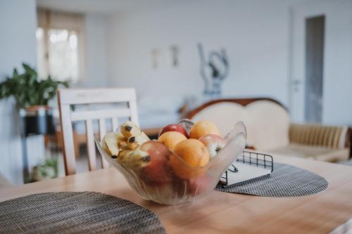 a glass bowl of fruit on a wooden table at MASAL Studio Apartman in Bihać
