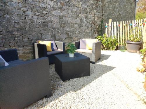 a patio with couches and tables and a stone wall at Gite des Mézières in Brusvily