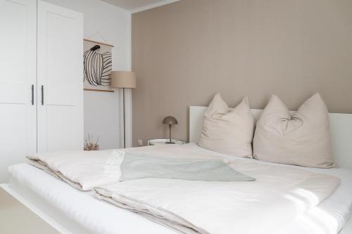 a white bed with white sheets and pillows at Soulplace Herten - warm & gemütlich in Herten
