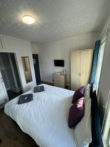 a bedroom with a large white bed with purple pillows at Burlington West hotel in Blackpool