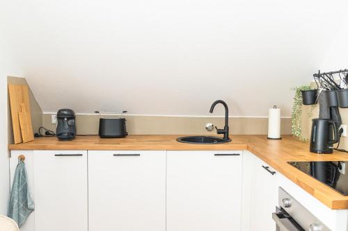 a kitchen counter with white cabinets and a sink at Soulplace Herten - warm & gemütlich in Herten