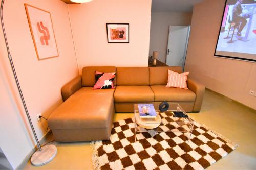 a living room with a brown couch and a checkered rug at Oasis SPA Bath et Jardin Parisien in Aubervilliers