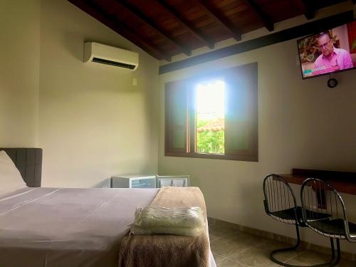 een slaapkamer met een bed en een tv aan de muur bij Pousada e Camping Recanto da Praia in Capitólio