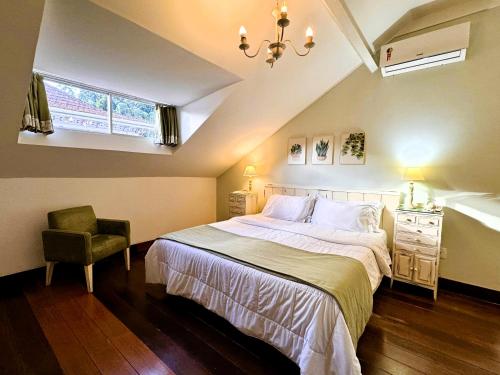 a bedroom with a bed and a chair and a window at Hotel Casablanca Imperial in Petrópolis