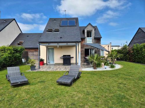 a yard with two chairs and a house at Les Charmilles in Escoville