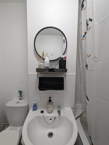 uma casa de banho branca com um lavatório e um espelho em Ali's Flat em Londres