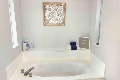 ein weißes Bad mit einer Badewanne mit einem Bild an der Wand in der Unterkunft Vacation Home with Private Pool in Dallas