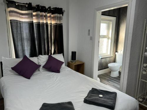 a bedroom with a white bed with purple pillows at Burlington West hotel in Blackpool