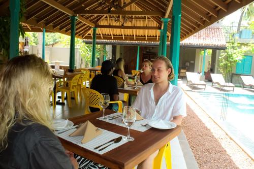 grupa ludzi siedzących przy stole w restauracji w obiekcie The Chariot Hikkduwa Resort w mieście Hikkaduwa