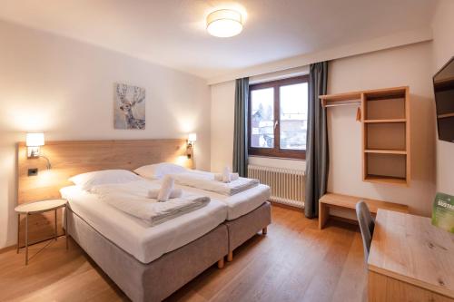 a hotel room with two beds and a window at Hotel Pinzgauerhof - Inclusive Evening Dinner in Saalbach Hinterglemm