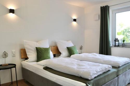 a bedroom with two beds with white and green pillows at Moderne EG-Wohnung im Günztal in Krumbach