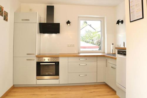 a kitchen with white cabinets and a window at Moderne EG-Wohnung im Günztal in Krumbach