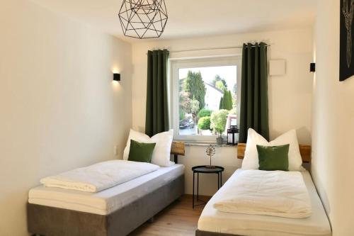 two beds in a room with a window at Moderne EG-Wohnung im Günztal in Krumbach