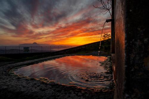 a pool of water with a sunset in the background at Case Ruggieri Luxury apt - Don Pietro in Gratteri