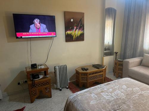 Appartement Wassim - Gueliz في مراكش: غرفة بتلفزيون على جدار مع سرير